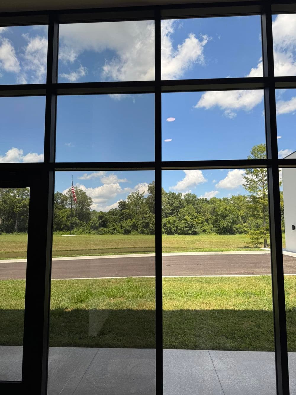 View of a clear blue sky and green landscape from a modern building's window.