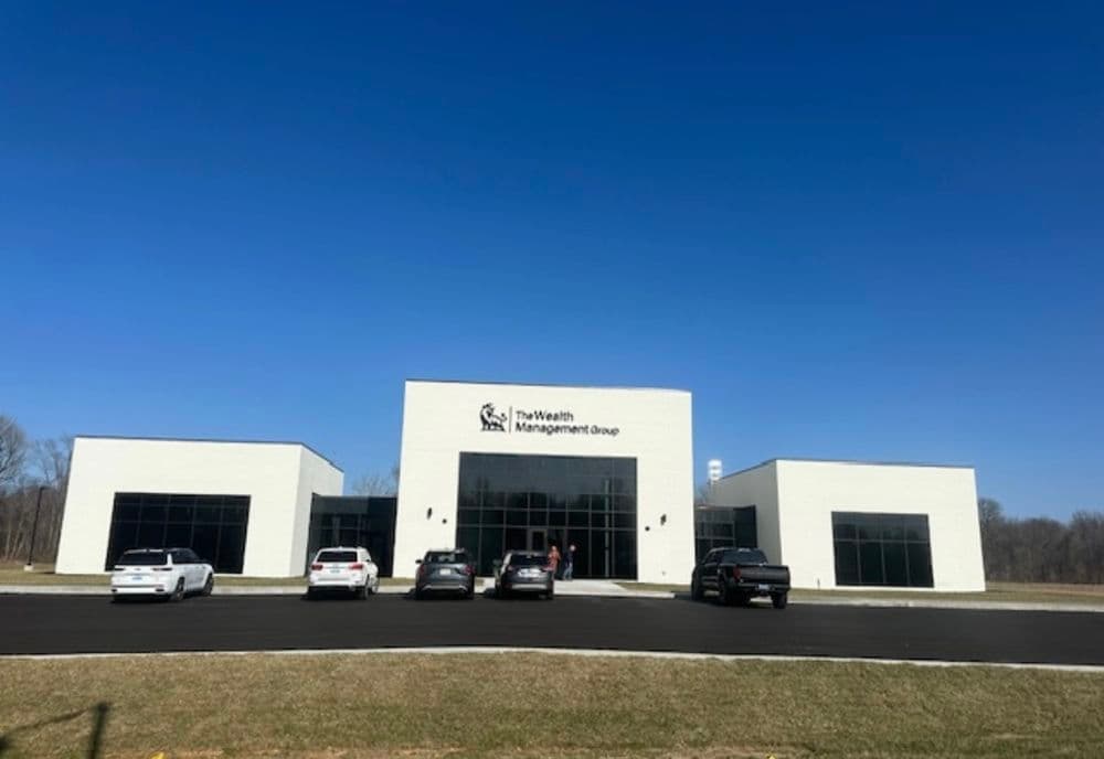 Modern wealth management office building with clear blue sky and parked cars.