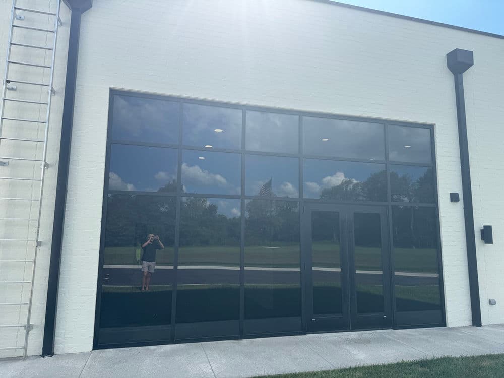 Modern commercial building facade with large reflective windows and double entrance doors.