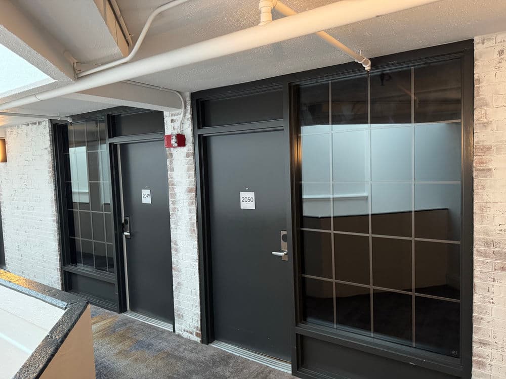 modern hotel hallway with three doors, numbered 2058, 2059, and 2060, reflecting natural light