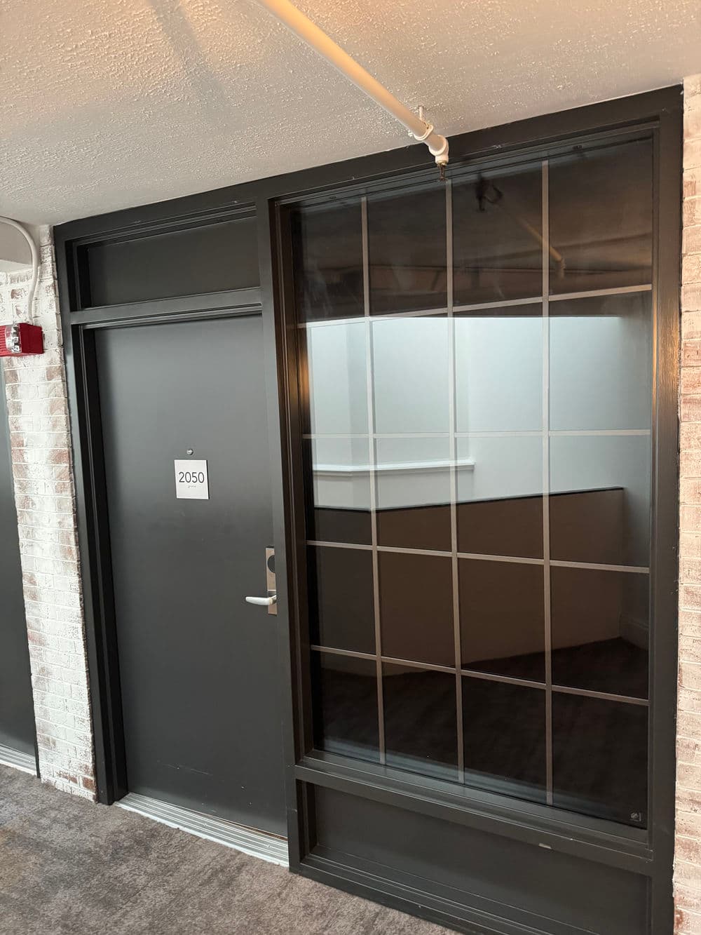 Modern office entrance with room number 2050 and large grid-patterned window.