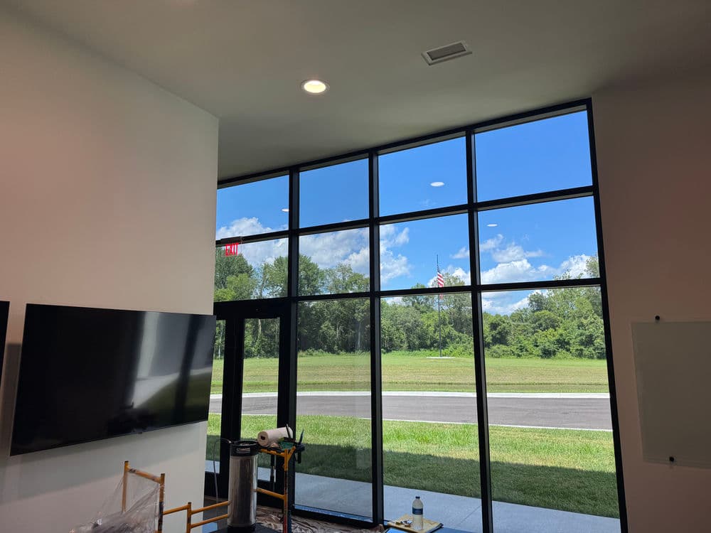 Modern interior showcasing large windows with scenic view of trees and blue sky.